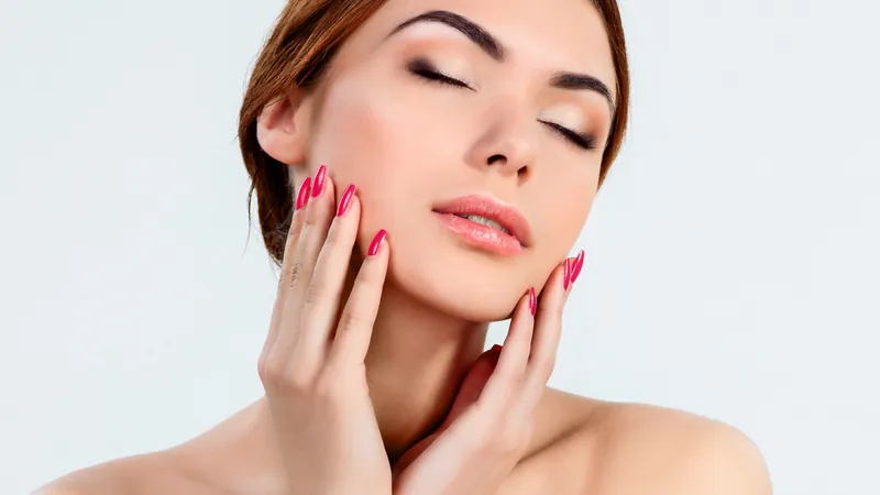 Frau, die ihr Gesicht mit beiden Händen umrahmt, mit natürlichem Make-up